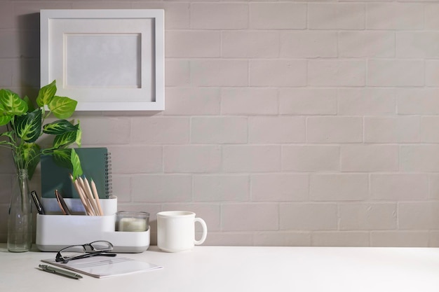 Cómodo lugar de trabajo con marco de fotos, taza de café, cuaderno y planta de casa Escritorio de oficina en casa Copie espacio para su texto