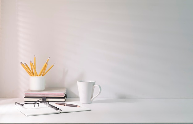 Cómodo lugar de trabajo con papelería de café y planta de interior en mesa blanca