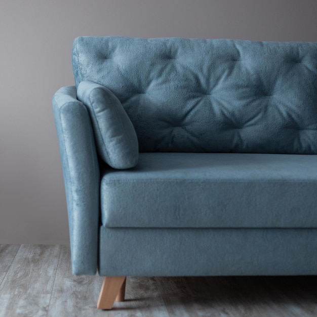 Cómodo sofá textil vintage azul sobre el fondo de una pared beige Interior de la habitación