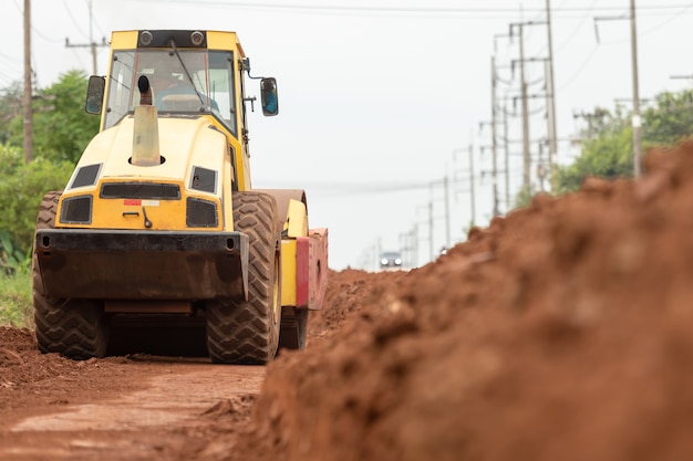 Compactador de suelo vibratorio amarillo trabajando en construcción de carreteras.