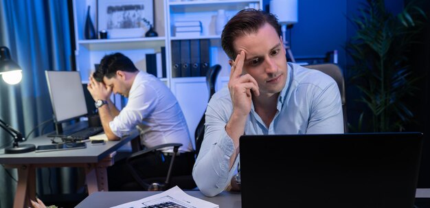 Compañero de trabajo estresado con dolor de cabeza trabajando en un nuevo proyecto por la noche