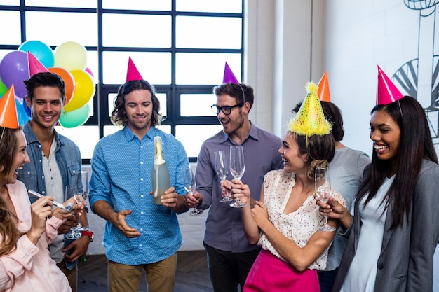 Compañero de trabajo feliz abriendo una botella de champán para cumpleaños