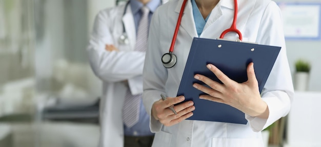 Compañeros médicos en uniforme posando en la clínica con papel de receta