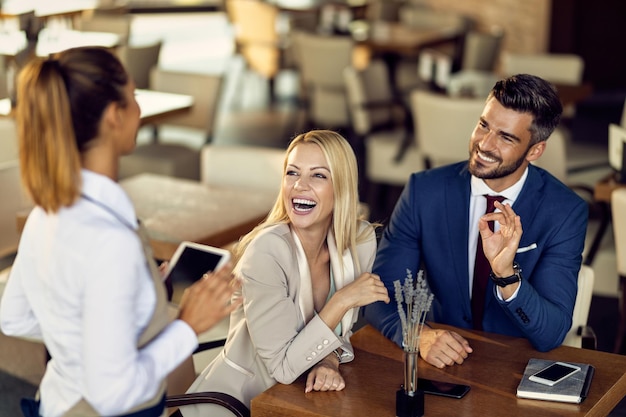 Compañeros de negocios alegres haciendo un pedido en un café