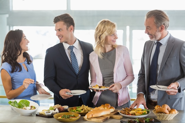 Foto compañeros de negocios interactuando mientras se sirven en el almuerzo buffet