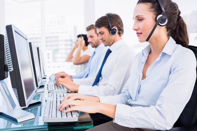 Compañeros de trabajo con auriculares usando computadoras