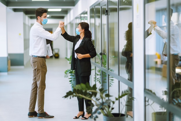 Compañeros de trabajo chocando los codos mientras se saludan en el trabajo.