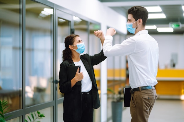 Compañeros de trabajo chocando los codos mientras se saludan en el trabajo.