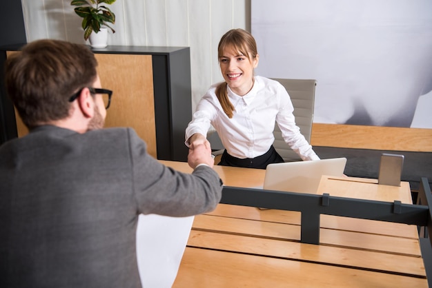 Compañeros de trabajo dándose la mano unos a otros en el lugar de trabajo