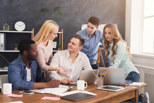 Compañeros de trabajo de la empresa discutiendo ideas y haciendo una lluvia de ideas en la oficina, equipo joven y exitoso que planea una nueva estrategia de marketing, espacio de copia