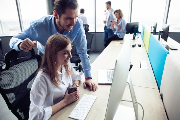 Compañeros de trabajo del equipo corporativo que trabajan en la oficina moderna.