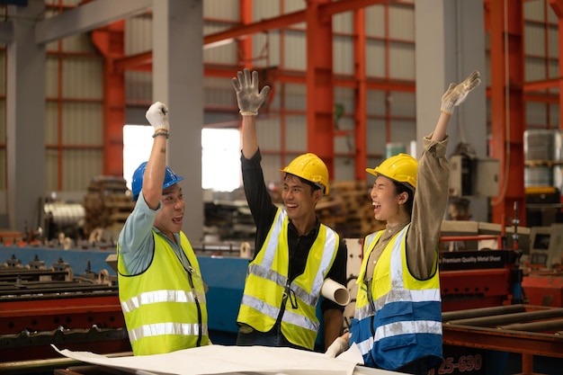 Compañeros de trabajo en equipo Técnicos y trabajadores ingenieros con casco o chaleco de casco que muestran la coordinación de las manos y levantan el puño sonriendo para trabajar con éxito en el lugar de trabajo de la fábrica de la industria