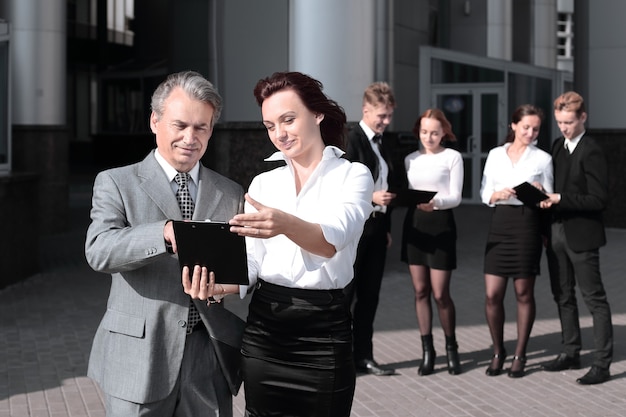 Compañeros de trabajo exitosos con documentos de pie frente al edificio de oficinas