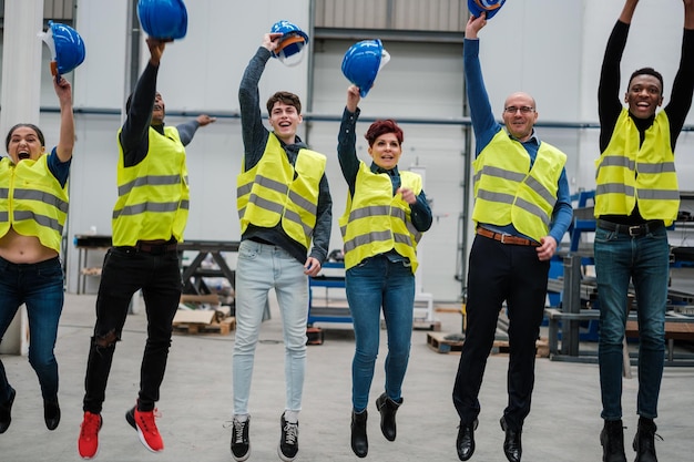 Compañeros de trabajo de una fábrica industrial saltando juntos alegremente