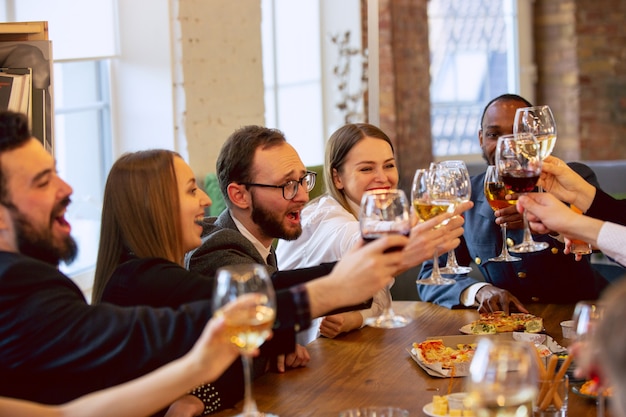 Compañeros de trabajo felices celebrando mientras la fiesta de la empresa y el evento corporativo. Jóvenes caucásicos en traje de negocios animando, riendo. Concepto de cultura de oficina, trabajo en equipo, amistad, vacaciones, fin de semana.