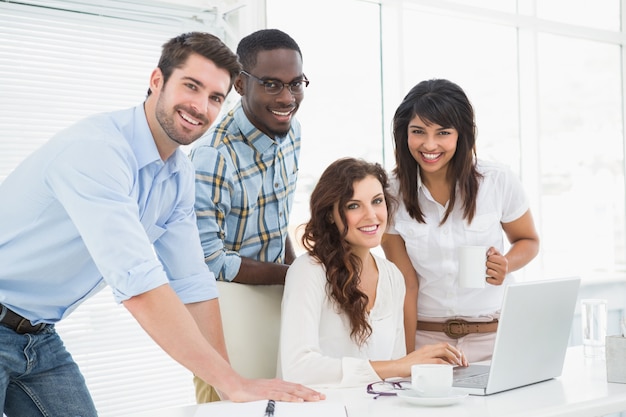 Foto compañeros de trabajo felices que trabajan junto con la computadora portátil