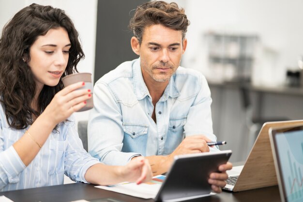 Compañeros de trabajo femeninos en coworking con computadoras, hombre maduro y joven caucásica