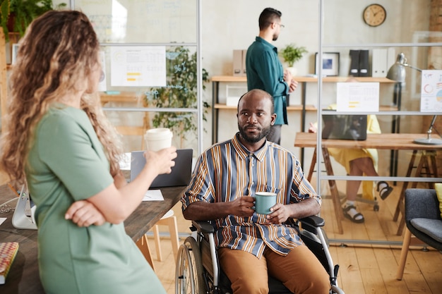 Compañeros de trabajo hablando entre sí y tomando café en la oficina durante la pausa para el café