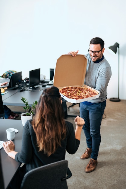 Compañeros de trabajo hambrientos almorzando en el lugar de trabajo. Comiendo pizza.