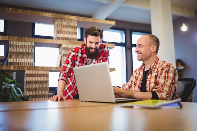 Compañeros de trabajo masculinos creativos discutiendo sobre laptop