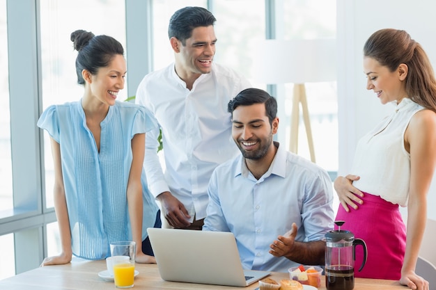 Compañeros de trabajo sonrientes discutiendo sobre portátil