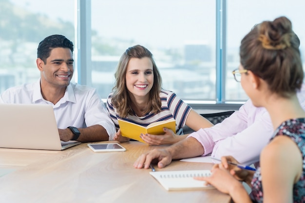 Compañeros de trabajo sonrientes interactuando entre sí en la reunión