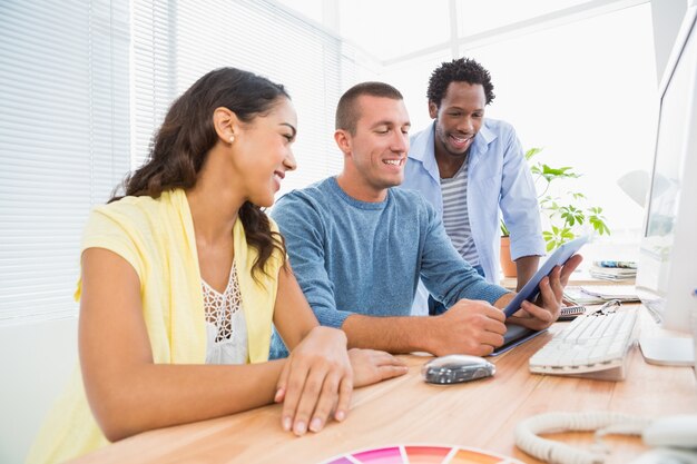 Compañeros de trabajo sonrientes que usan la tableta junto