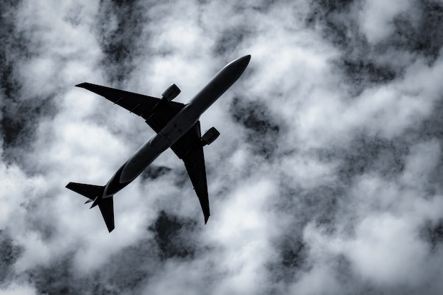 Companhia aérea comercial voando no céu escuro e nuvens macias brancas.