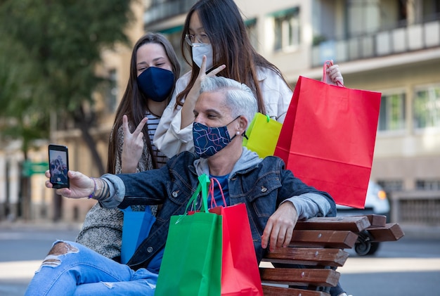 Compañía de amigos en máscaras tomando selfie en ciudad