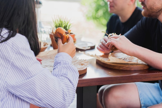 Una compañía de amigos se reunió para almorzar en un café de verano charlando y comiendo hamburguesas