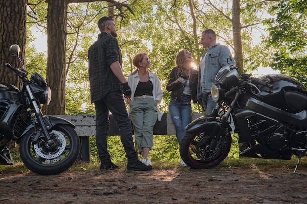 Una compañía de amigos viaja juntos en motocicletas paradas en la carretera, se divierten y beben té.