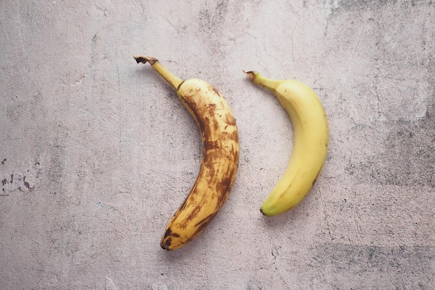 Comparando plátano podrido con un plátano maduro sobre un fondo blanco.