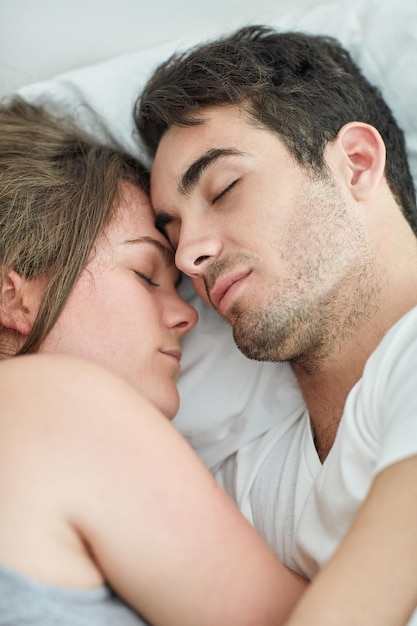 Compartiendo los momentos que importan Toma de una pareja joven relajada durmiendo en la cama juntos en casa