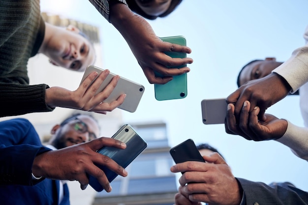 Compartiendo noticias importantes. Toma de un grupo de empresarios usando teléfonos afuera.