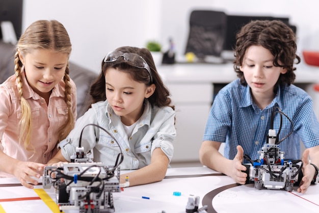 Compartiendo opiniones. Alumnos positivos hábiles, animados, sentados en la escuela y disfrutando de la clase de ciencias mientras expresan curiosidad y conversan