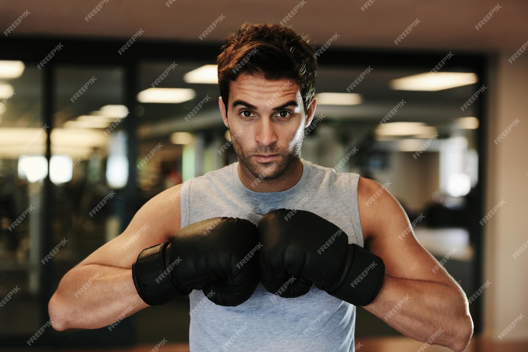 Competidor ferozmente enfocado retrato de un hombre enfocado usando guantes de boxeo y ropa deportiva posando listo para el gimnasio | Foto Premium