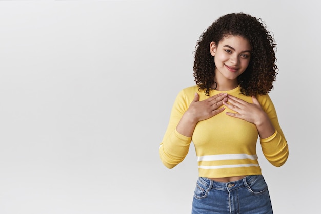 Foto complacido niña feliz recibir regalo satisfecho encantadora morena pelo rizado mestizo novia prensa manos pecho sonriendo encantado agradecido agradeciendo amigo bonito cumpleaños presente agradecido mirar cámara