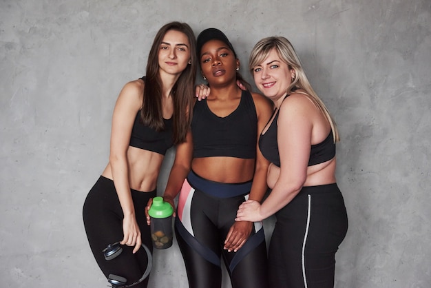 Foto los complementos alimenticios siempre son importantes antes y después del entrenamiento. grupo de mujeres multiétnicas de pie