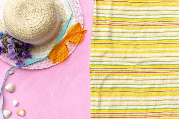 Complementos para las vacaciones de verano con sombrero de paja y manta con gafas de sol.