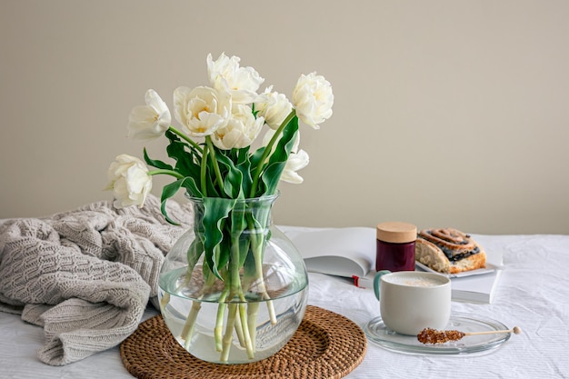 Composição aconchegante com um buquê de flores café e um pão na cama