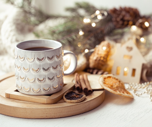 Composição aconchegante com uma xícara de Natal com uma bebida quente e canela em um fundo desfocado. Conceito de aconchego de inverno em casa.