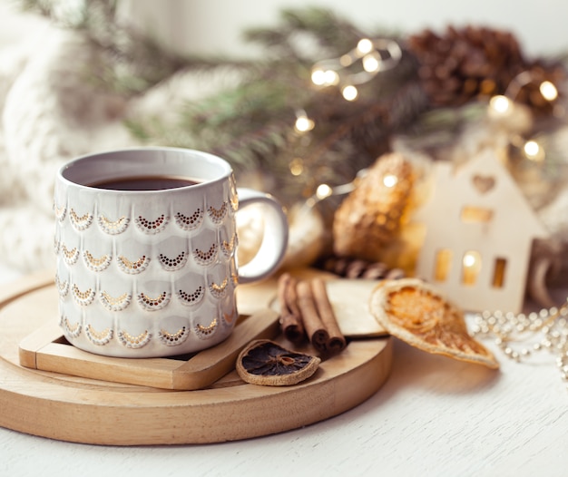 Composição aconchegante com uma xícara de natal com uma bebida quente e canela em um fundo desfocado. conceito de aconchego de inverno em casa.