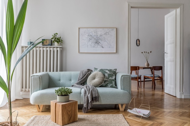 Composição aconchegante e criativa de design de interiores de sala de estar elegante com mock up moldura de pôster, sofá verde, móveis de madeira, plantas e acessórios. paredes brancas, chão em parquet. modelo.