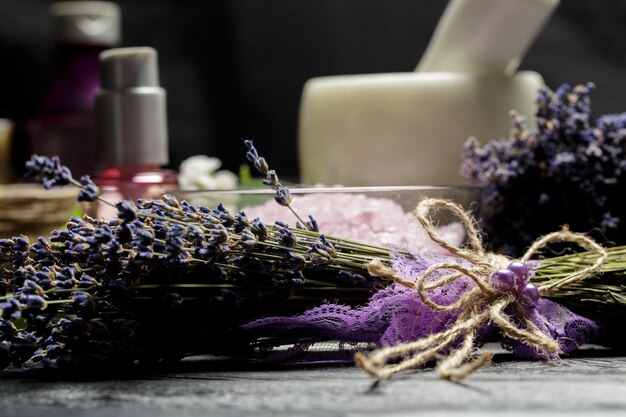 Composição aromática de lavanda, ervas, cosméticos e sal em cima de uma mesa escura