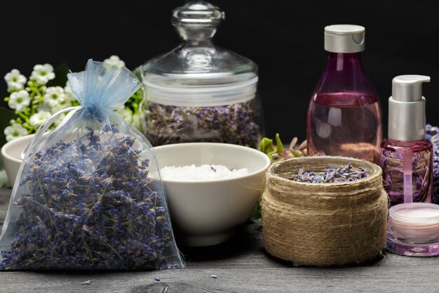 Composição aromática de lavanda, ervas, cosméticos e sal em mesa escura