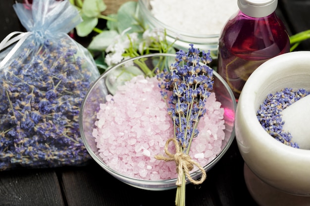 Composição aromática de lavanda, ervas, cosméticos e sal em um tampo de mesa escuro