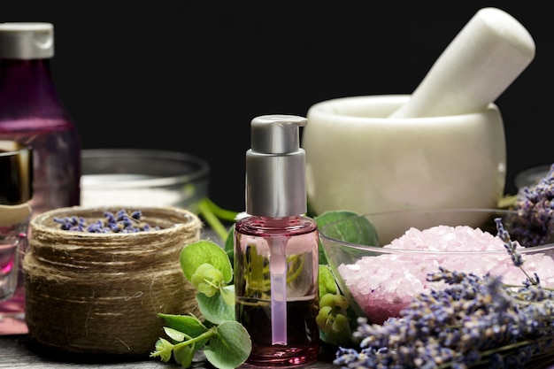 Composição aromática de lavanda, ervas, cosméticos e sal em um tampo de mesa escuro