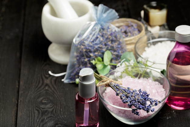 Composição aromática de lavanda, ervas, cosméticos e sal em um tampo de mesa escuro