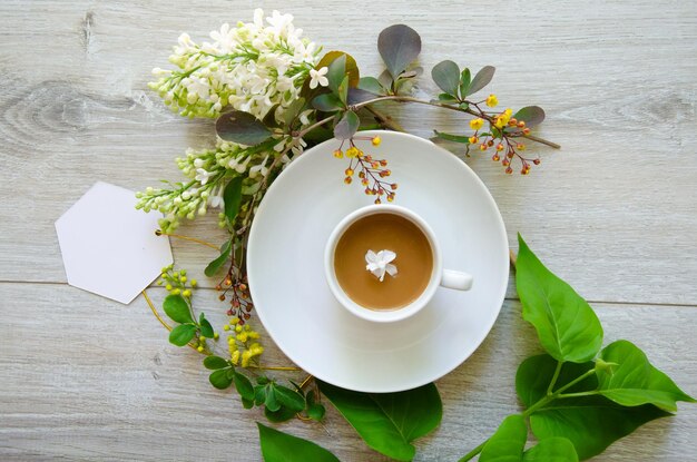 Foto composição central plana com uma xícara de café em um prato com um modelo de um cartão branco vazio