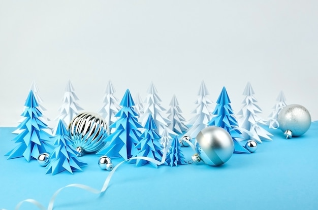 Composição com árvores de Natal de papel azul e branco e enfeites de bola